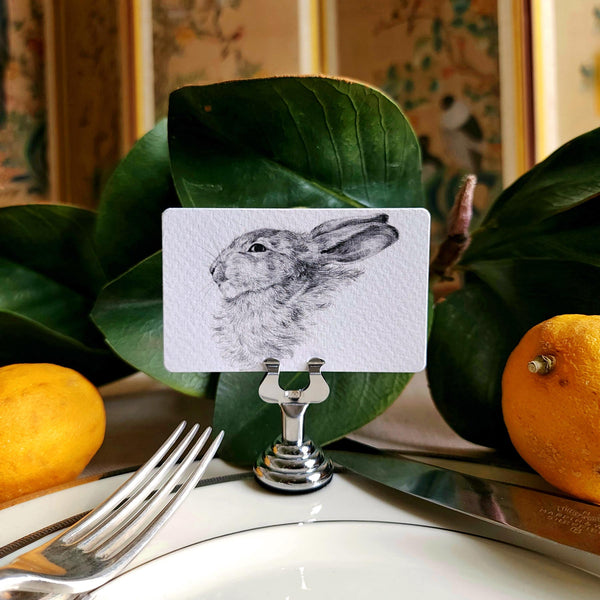 The Punctilious mr. P's Pace Card Co. "Bunny" custom place card on a silver place card holder with magnolia leaves and lemons in the background against a chinoiserie screen
