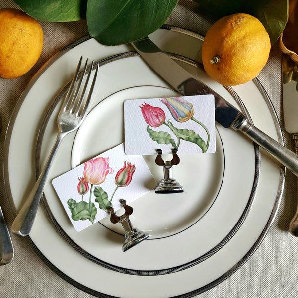 showing all two of The Punctilious mr. P's Pace Card Co. "Parrot Tulips" custom place card on a silver place card holder with magnolia leaves and lemons in the background against a chinoiserie screen