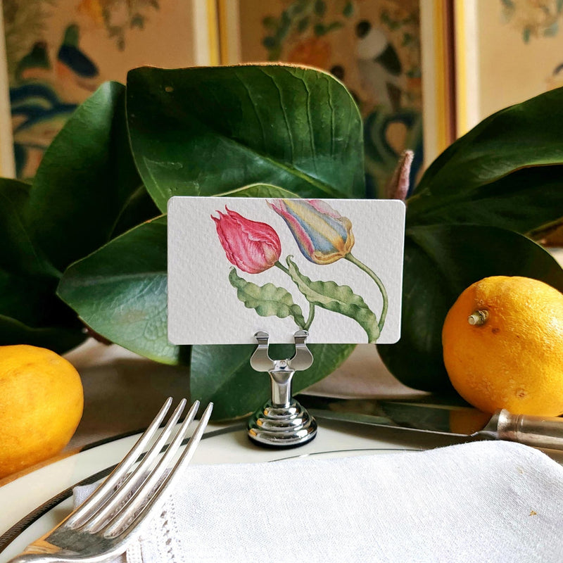 The Punctilious mr. P's Pace Card Co. "Parrot Tulips" custom place card on a silver place card holder with magnolia leaves and lemons in the background against a chinoiserie screen