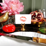 The Punctilious mr. P's Pace Card Co. "kisses" custom place card on a gold place card holder with flowers and a pomegranate in the background