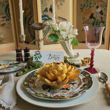 Decorative table setting with a 'Betsy' name place card and yellow ceramic blossom centerpiece.
