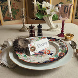 video of Robin's Egg place card on decorative plate with flowers in the background. 