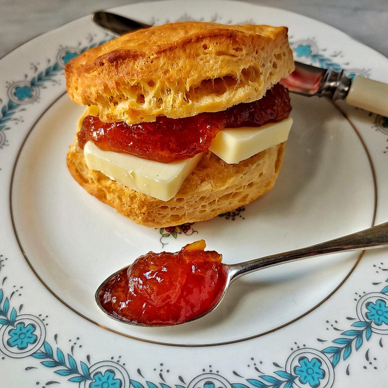 a buttered biscuit with mr. p's pantry marmalade on a fine porcelain saucer