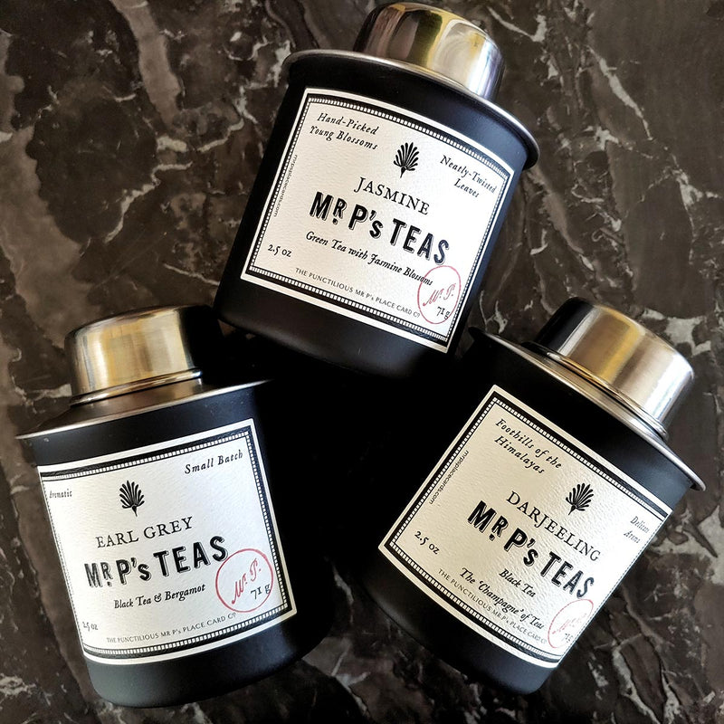 The Punctilious Mr. P's tea trio of Earl Grey, jasmine and darjeeling Tea canisters on black and grey marble tabletop