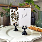 The Punctilious Mr. P's Place Card Co. 'Ivy' custom place card set showing a name printed in digital calligraphy in spencerian font resting on white china with bamboo cutlery and live potted ivy in the background