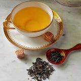 The Punctilious Mr. P's Jasmine flavored loose green Tea on marble table with tea cup and saucer and brown square sugar cubes