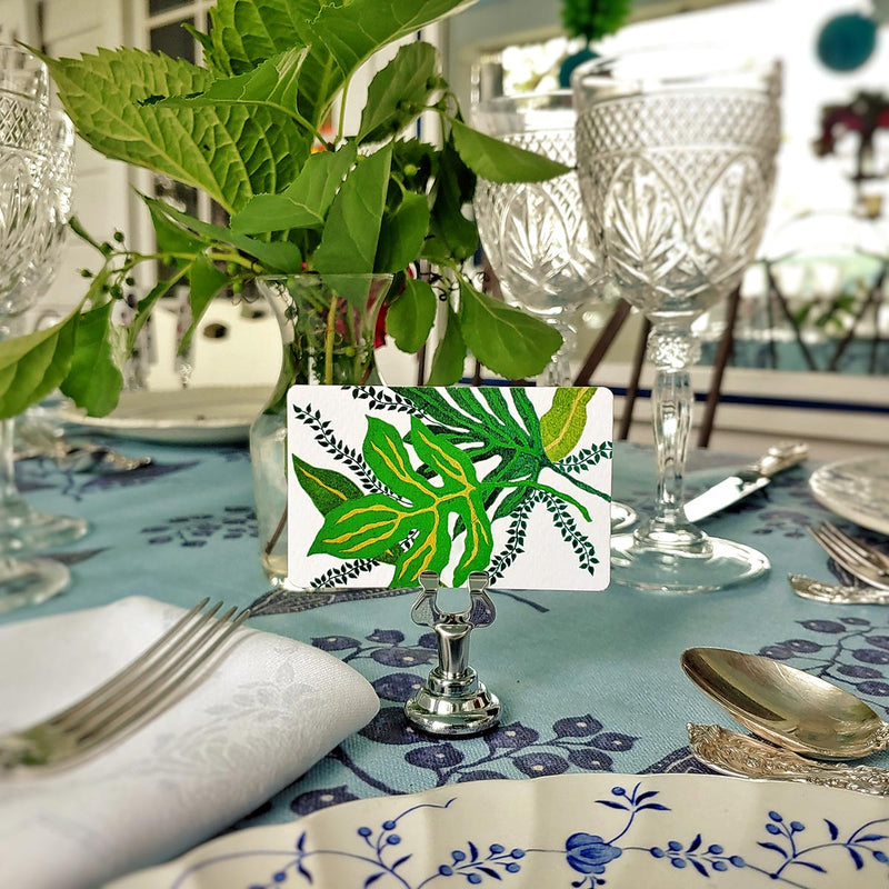 Marian McEvoy x The Punctilious Mr. P's Place Card Co collab with tropical green floral custom illustrated place cards on a table with silverware and beautiful green leaves in vase