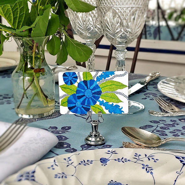 Marian McEvoy x The Punctilious Mr. P's Place Card Co collab with tropical blue and green floral Custom  illustrated place cards on a table with silverware and cut crystal glasses