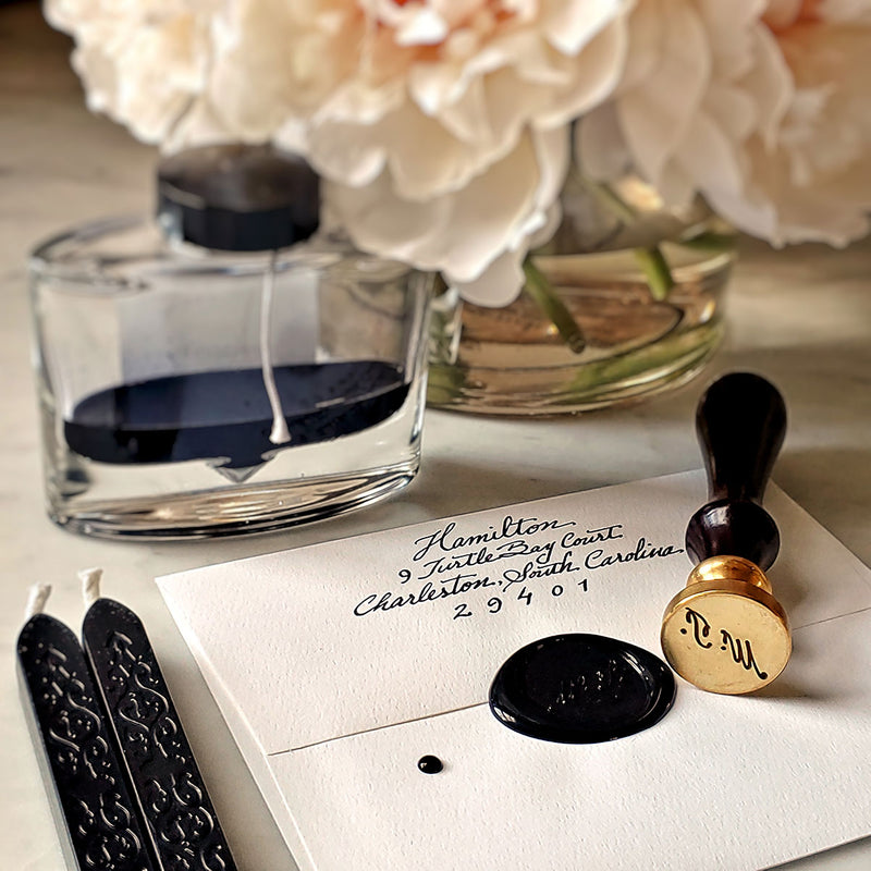 The Punctilious Mr. P's Place Card Co. custom wax seal with 2 black wax sticks, ink bottle and beautiful vase of peony flowers