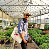mr. p's co-founder martin cooper in the greenhouse at the berry farm carrying the everyday tote bag on his shoulder